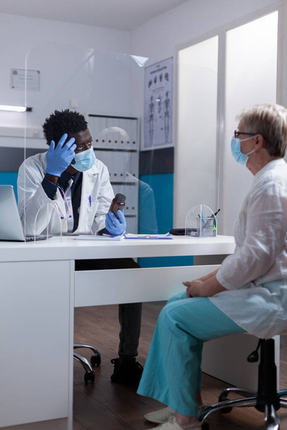 Medyk pochodzenia afrykańskiego rozmawiający ze starym pacjentem - Zdjęcie, obraz