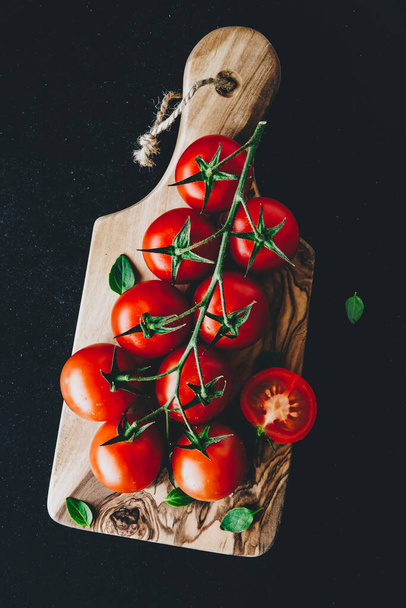 Tomatoes. Sweet ripe organic cherry tomatoes on a branch on wooden cutting board. - Φωτογραφία, εικόνα