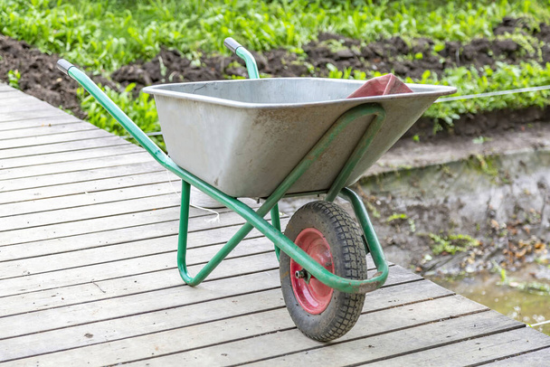 Iron wheel barrow for moving of building materials in the garden and in the backyard - Photo, Image