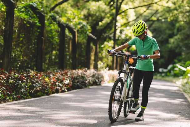 Woman going to ride on bike path at park on sunny day - Photo, image