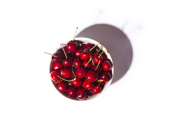 top view of a bowl full of cherries with white background. Healthy food concept. - Photo, Image