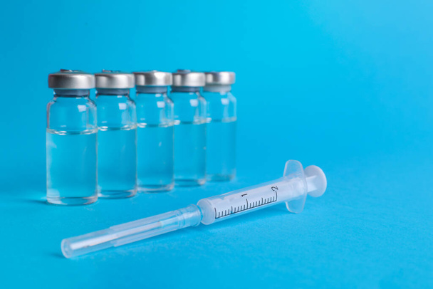 Disposable syringe with needle and vials on light blue background - Fotografie, Obrázek