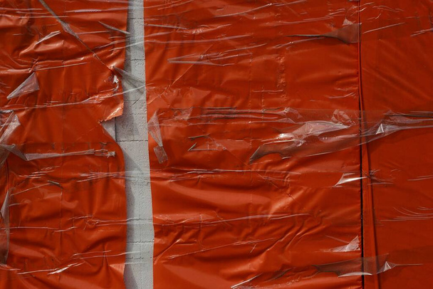 κόκκινη πλαστική υφή από τσαλακωμένο σελοφάν τυλιγμένο με λευκή τρύπα - Φωτογραφία, εικόνα