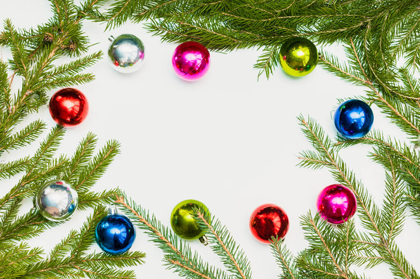 Weihnachtskomposition mit leerem Rahmen aus bunten Kugeln und Tannenzweigen. Ornament, Neujahrsdekorationen auf weißem Hintergrund. Grußkarten-Attrappe mit Kopierraum, flach, Ansicht von oben. - Foto, Bild