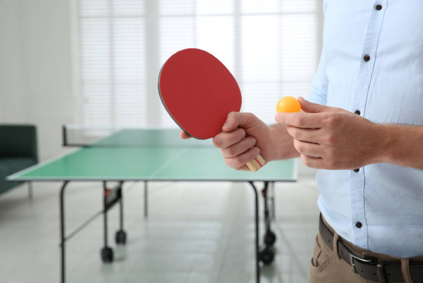 Businessman with tennis racket and ball near ping pong table in office, closeup. Space for text - Valokuva, kuva