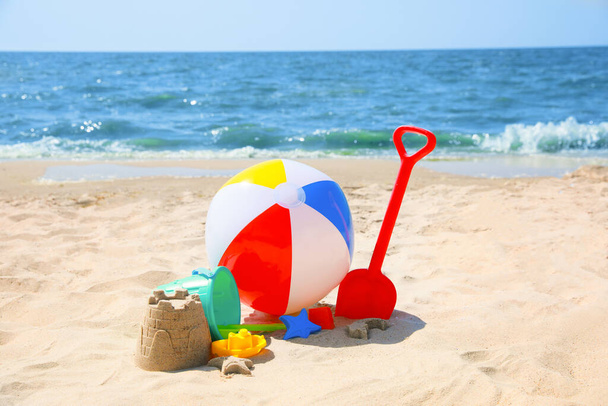 Different sand toys and beach ball near sea - Фото, зображення