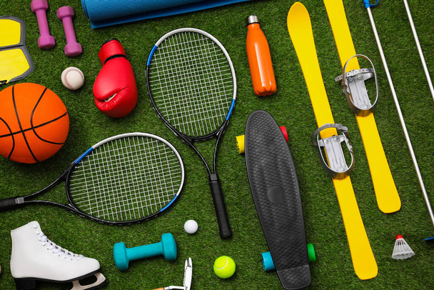 Different sport equipment on green grass, flat lay - Fotoğraf, Görsel