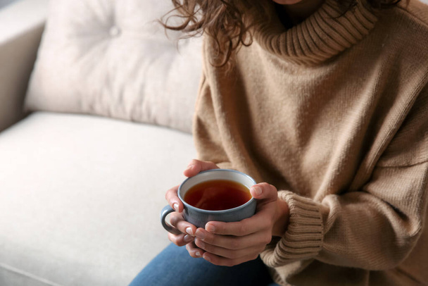 Woman with cup of hot tea indoors, closeup. Cozy home atmosphere - Foto, Bild