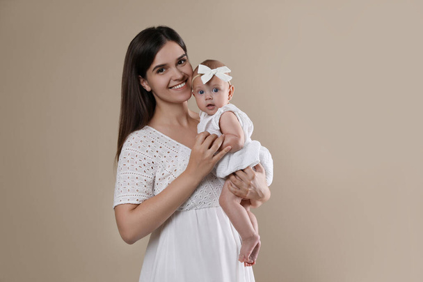 Beautiful mother with her cute baby on beige background - Foto, Imagem