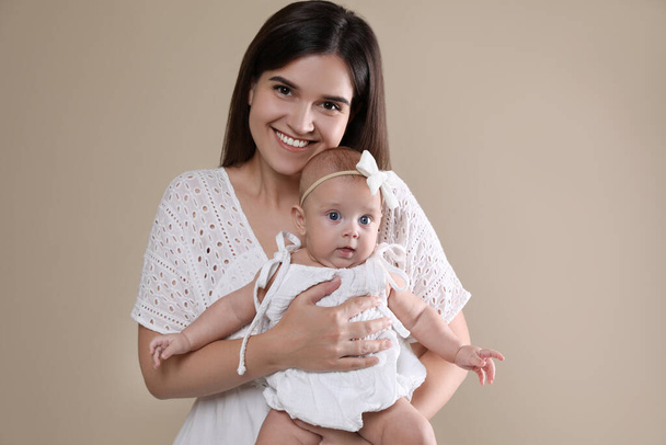 Beautiful mother with her cute baby on beige background - Photo, image