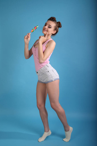 young woman with candy on a blue background - Foto, Imagem