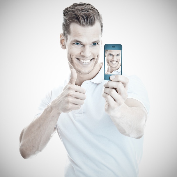 χαρούμενος νεαρός άνδρας λαμβάνοντας ένα selfie με ένα σύγχρονο smartphone - Φωτογραφία, εικόνα