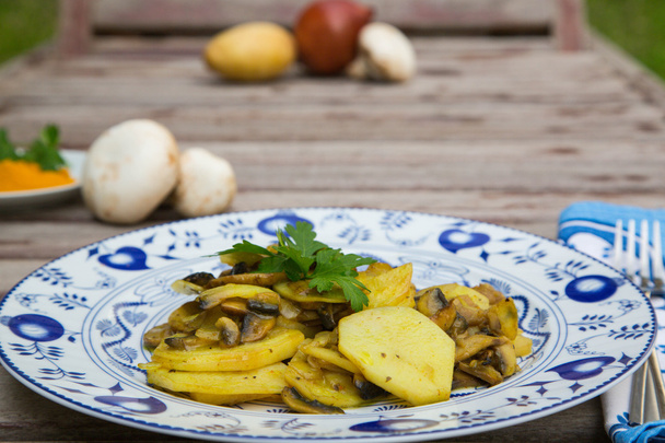 Запеченный картофель с грибами и петрушкой на белом голубом блюде
 - Фото, изображение