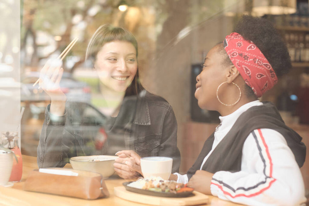 Две счастливые молодые перехватчицы едят в кафе - Фото, изображение