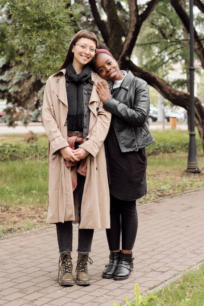 Two young affectionate females in casualwear standing on road - Фото, зображення