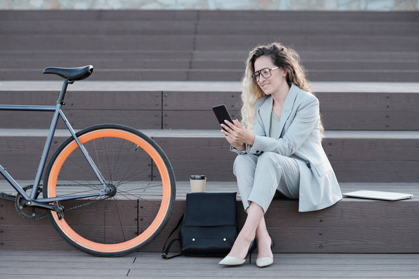 Ευτυχισμένη επιχειρηματίας κοιτάζοντας οθόνη smartphone, ενώ έχουν διάλειμμα - Φωτογραφία, εικόνα