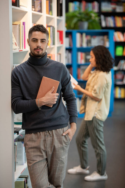Joven estudiante en ropa casual sosteniendo el libro junto a su pecho - Foto, imagen