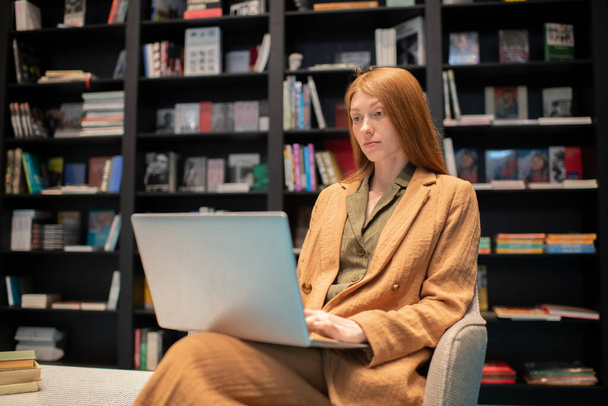 Mujer joven con portátil mirando a través de e-book en la pantalla - Foto, imagen