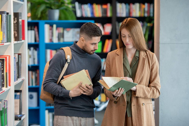 Two young students choosing books in library or bookshop - Photo, image