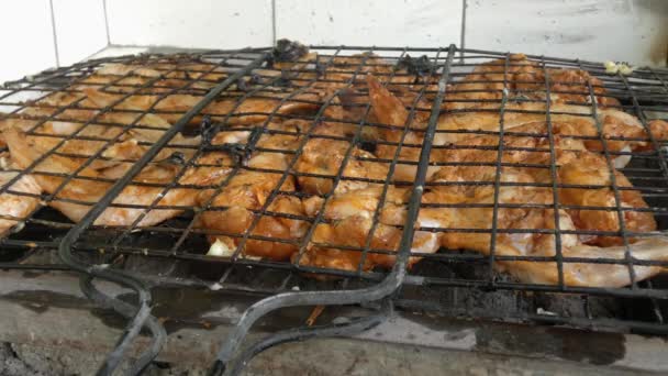 La griglia grattugia e cuoce le ali di pollo su carboni ardenti. Sopra di loro sorge un fumo profumato. - Filmati, video