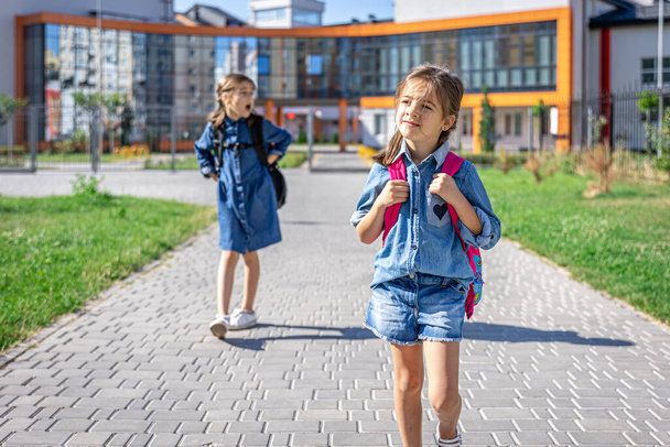 Pupils of primary school. Girls with backpacks near building outdoors. Beginning of lessons. First day of fall. - Fotografie, Obrázek