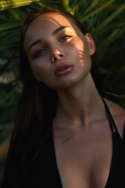 beautiful summer girl in palm leaves during sunset. young woman in bikini under palm tree. Beauty Portrait - Φωτογραφία, εικόνα