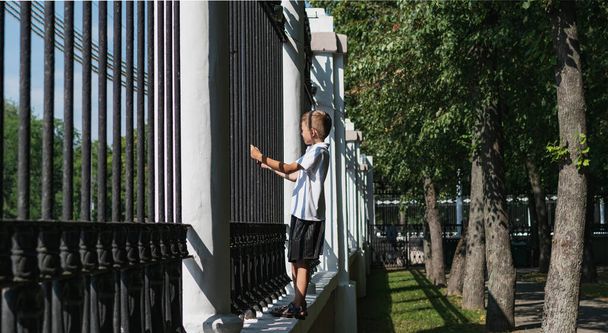 A small boy tries to climb a large metal fence - Fotoğraf, Görsel