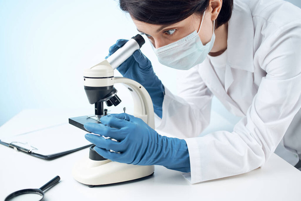 женщина-врач просматривает лабораторию биотехнологий микроскопа - Фото, изображение
