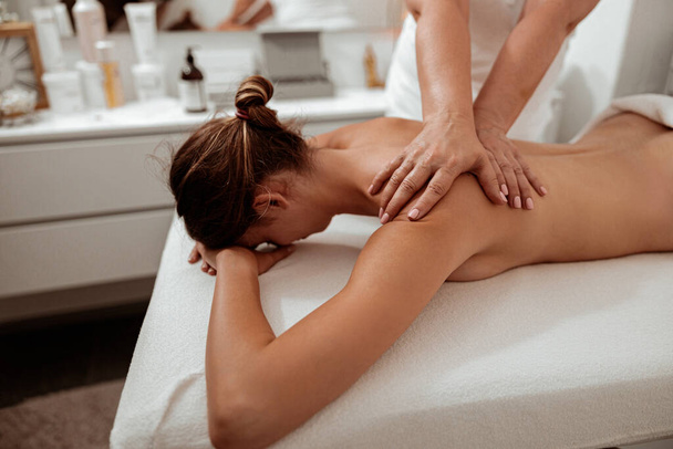 Cliente femenino recibiendo masaje terapéutico en salón de spa - Foto, imagen
