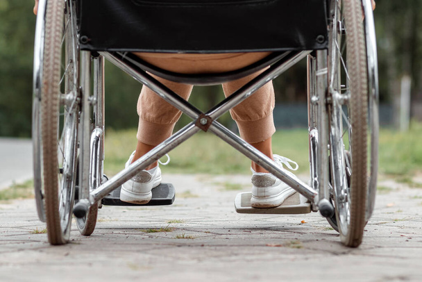 Close-up of legs in a wheelchair. The girl is disabled. The concept of a wheelchair, disabled person, full life, paralyzed, disabled person, health care - Foto, Bild
