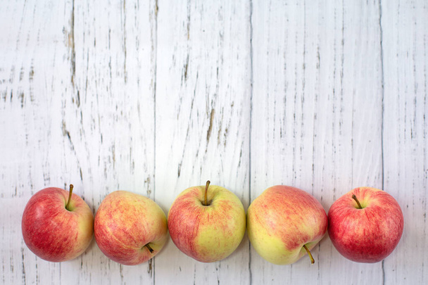 Manzanas rojas deliciosas maduras sobre un fondo de madera clara, vista superior. Nueva cosecha de verano. El concepto de comida saludable - Foto, Imagen