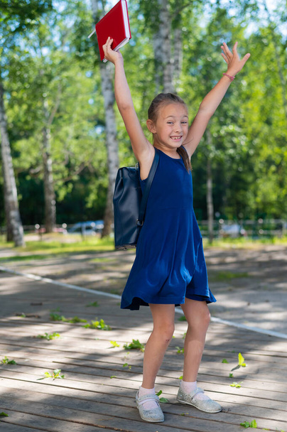 Joyful schoolgirl jumping outdoors. End of summer vacation and start of the primary school year - Foto, imagen