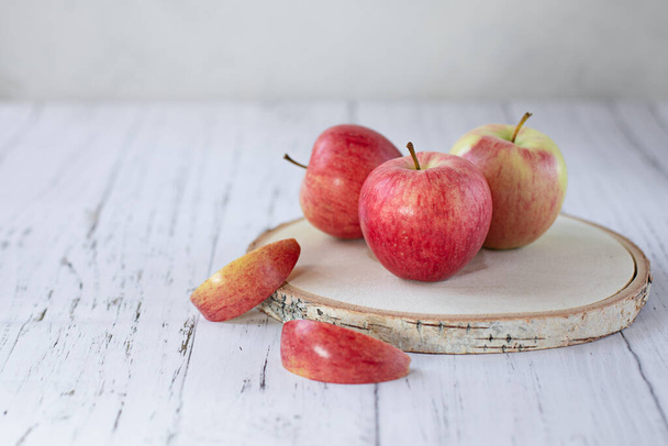 Ripe red apples on a wooden round stand on a light background. Sawing wood. New summer harvest. The concept of healthy food. - Foto, Imagen