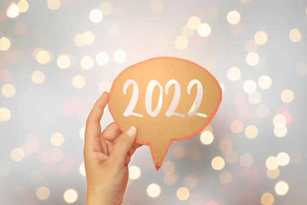 detailní ruka drží chatu bublina s šťastný nový rok 2022, 2022 Nový rok blahopřání šablona s bokeh rozmazané pozadí - Fotografie, Obrázek