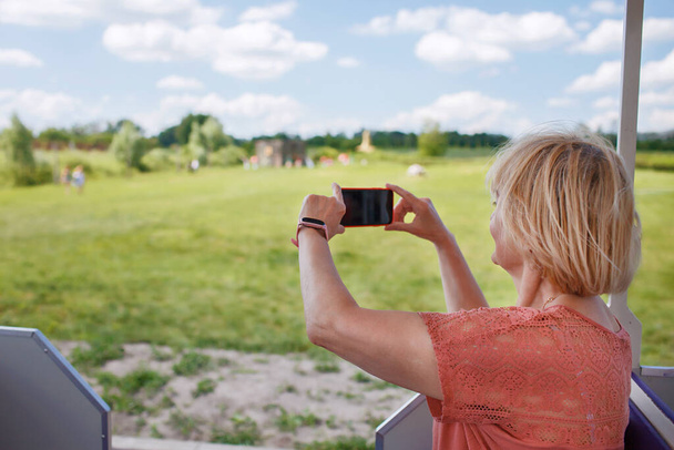 Turistik bir araçla gezerken akıllı telefondan fotoğraf çeken mutlu turist kadın. - Fotoğraf, Görsel