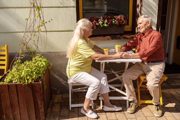 ストリートカフェの小さなテーブルで肯定的なシニアペアの恋人 - 写真・画像