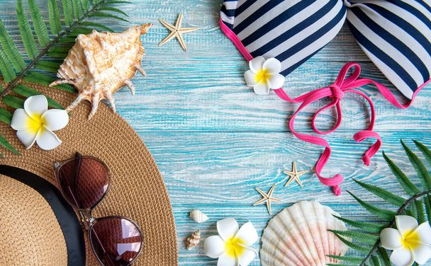 Καλοκαιρινές διακοπές. Ψάθινο καπέλο και αξεσουάρ παραλίας με κοχύλια και αστερίες σε μπλε ξύλινο φόντο - Φωτογραφία, εικόνα