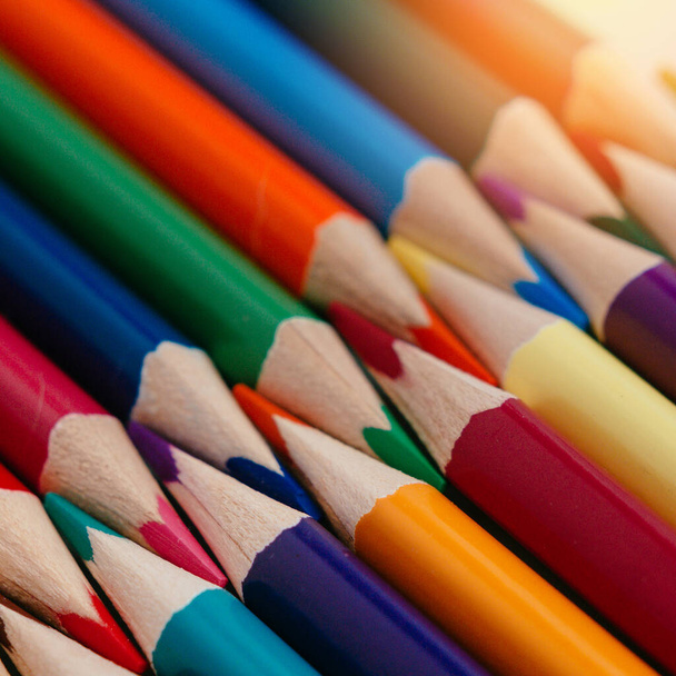 Colored sharpened pencils lie in a row close-up. Solid abstract background of wooden multi-colored pencils. - Zdjęcie, obraz