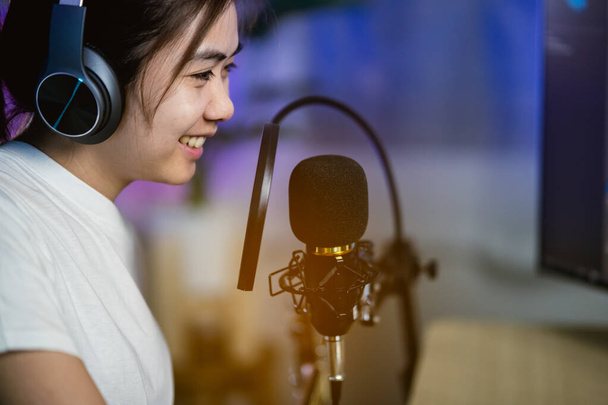 zangeressen zingen met hoofdtelefoon opnemen nieuw lied in de home recording studio - Foto, afbeelding