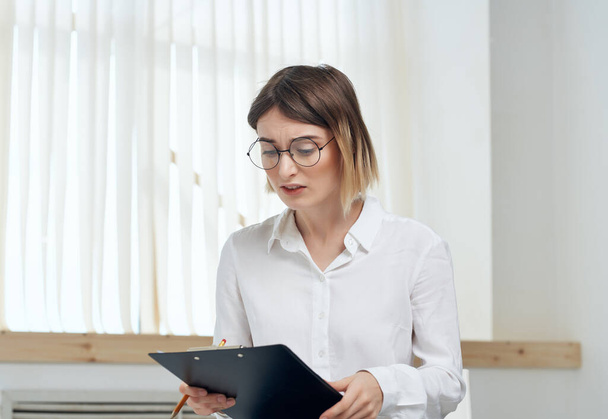 Zakelijke vrouw in wit shirt met map in handen voor kantoor papieren - Foto, afbeelding