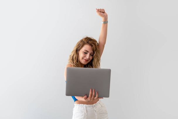 Young , beautiful woman hold her fist up and become happy, while she see the results on the screen. Victory and success concept - Foto, immagini