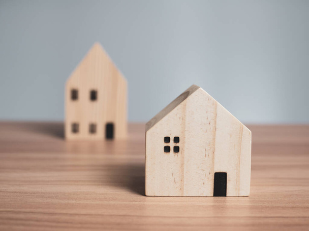 Dwa drewniane modele domów umieszczone na drewnianym stole. z jasnoszarym tłem - Zdjęcie, obraz