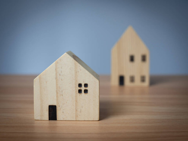 Deux maisons modèles en bois placées sur une table en bois. avec un fond gris clair - Photo, image