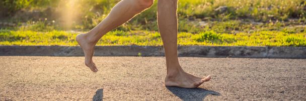 Ένας άνδρας δρομέας ασχολείται με το τρέξιμο στην άσφαλτο χωρίς παπούτσια, χωρίς αθλητικά παπούτσια, για την υγεία BANNER, LONG FORMAT - Φωτογραφία, εικόνα
