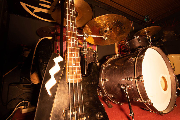 басовые музыкальные инструменты и барабаны в репетиционной комнате блюзово-рок-н-рольной группы - Фото, изображение