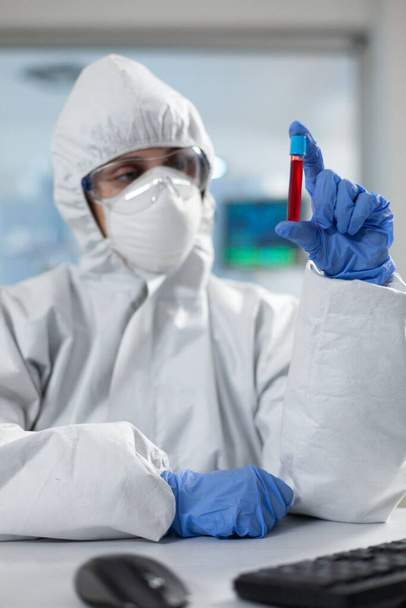 Дослідник хімії з захисним костюмом проти ковадла19 тримає медичного підприємця
 - Фото, зображення