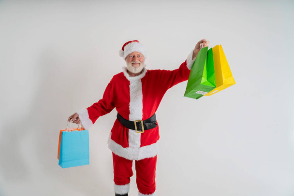 grijs haar bebaarde santa claus gaan winkelen hold x-mas kerst tassen op een witte achtergrond, met kerstcadeau zak - Foto, afbeelding