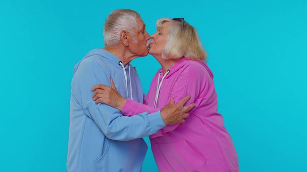 Romântico casal sênior homem mulher avós fazendo lotes de beijos olhando para a câmera e sorrindo - Foto, Imagem
