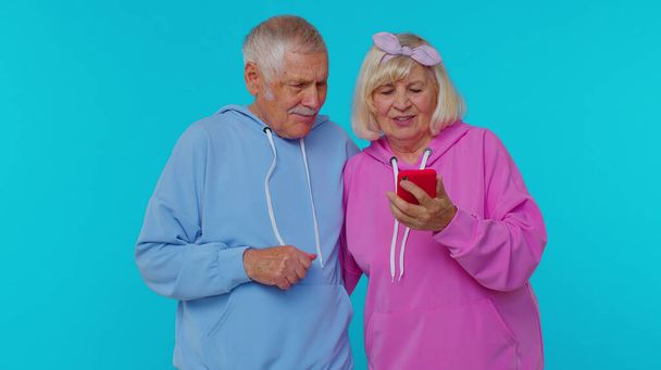 Gelukkig senior koppel man vrouw grootouders gebruiken mobiele telefoon vieren ontdekte grote overwinning nieuws - Foto, afbeelding