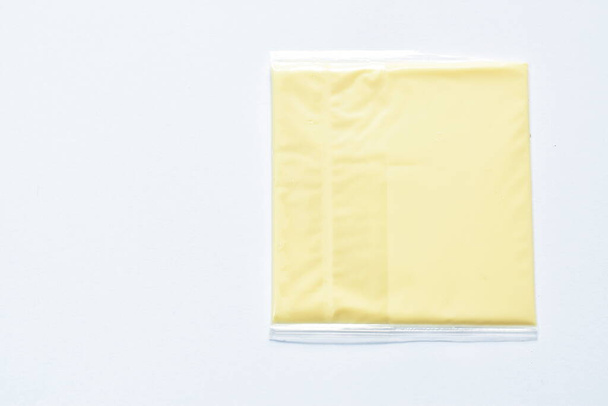  queso cuadrado en embalaje de plástico transparente sobre fondo blanco - Foto, Imagen